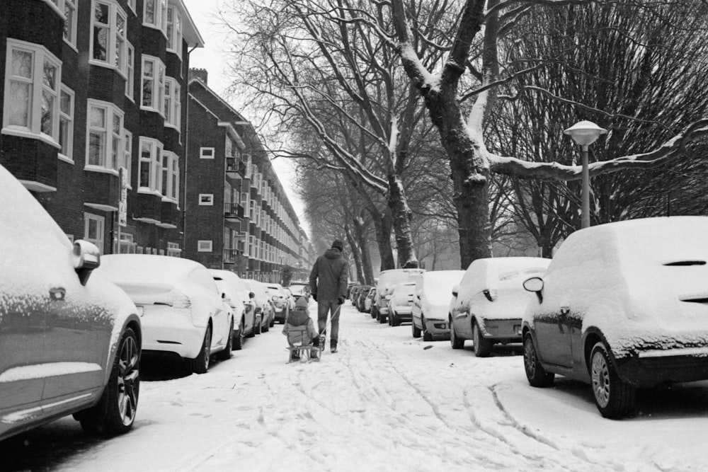 man in black jacket walking on snow covered road during daytime