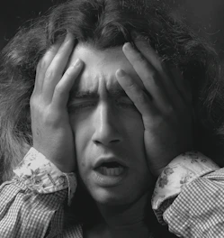A tense person holding their head, overwhelmed by stress.