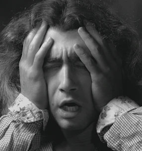A tense person holding their head, overwhelmed by stress.