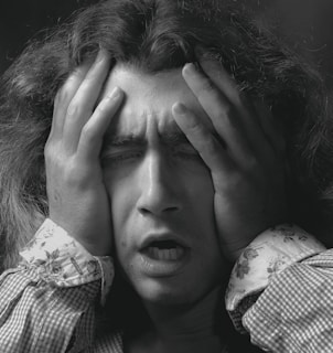Close-up of a person holding their head, showing signs of a headache.