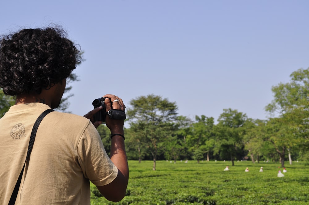 man in brown t-shirt holding camera