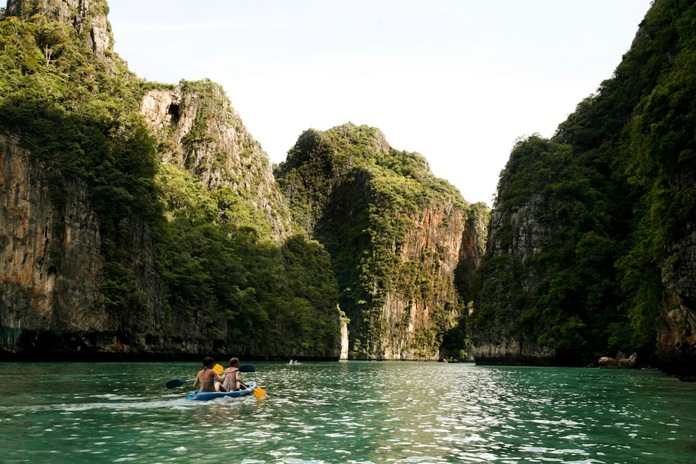 people riding on kayak on river near mountain during daytime