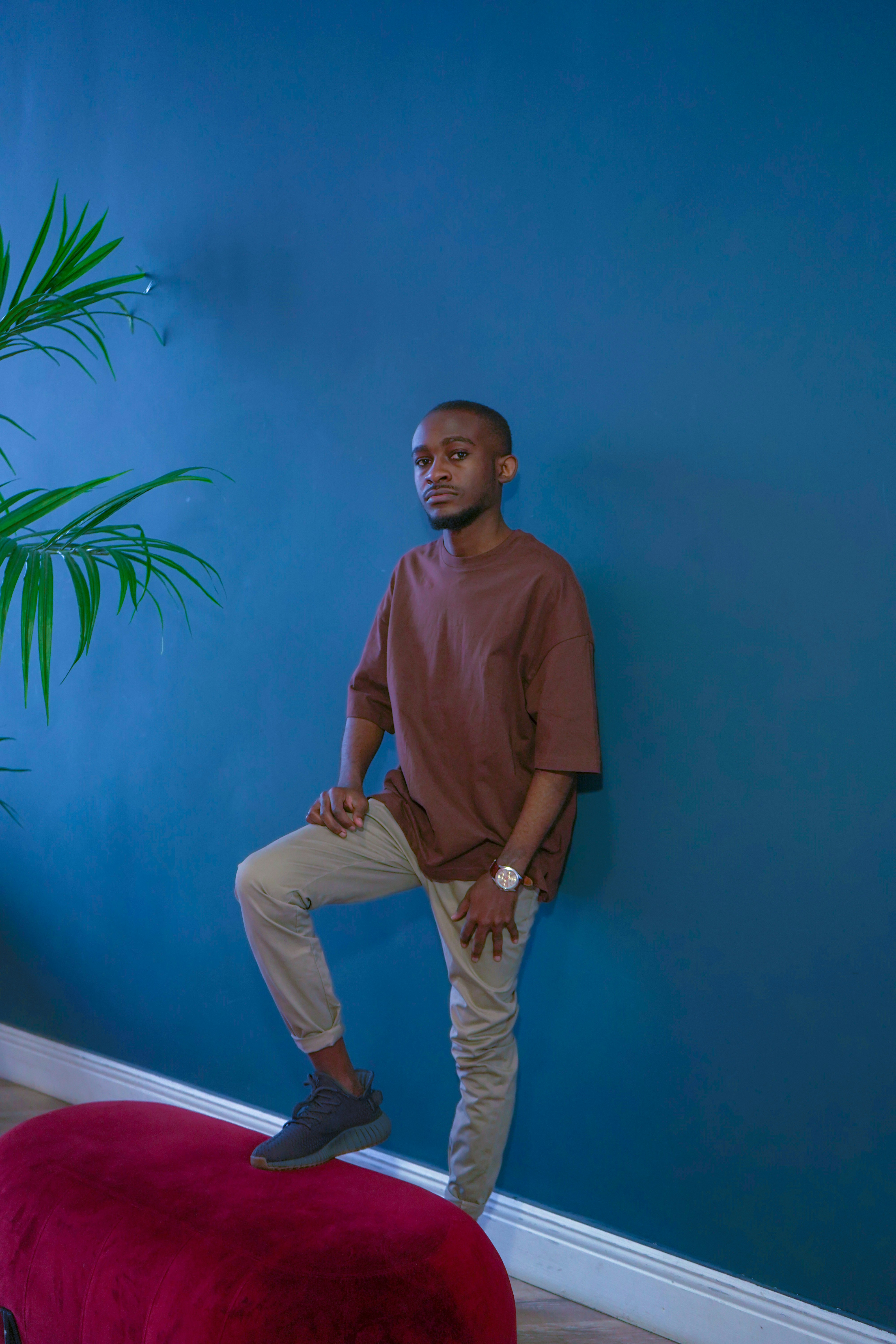 man in brown polo shirt and white pants standing beside green plant
