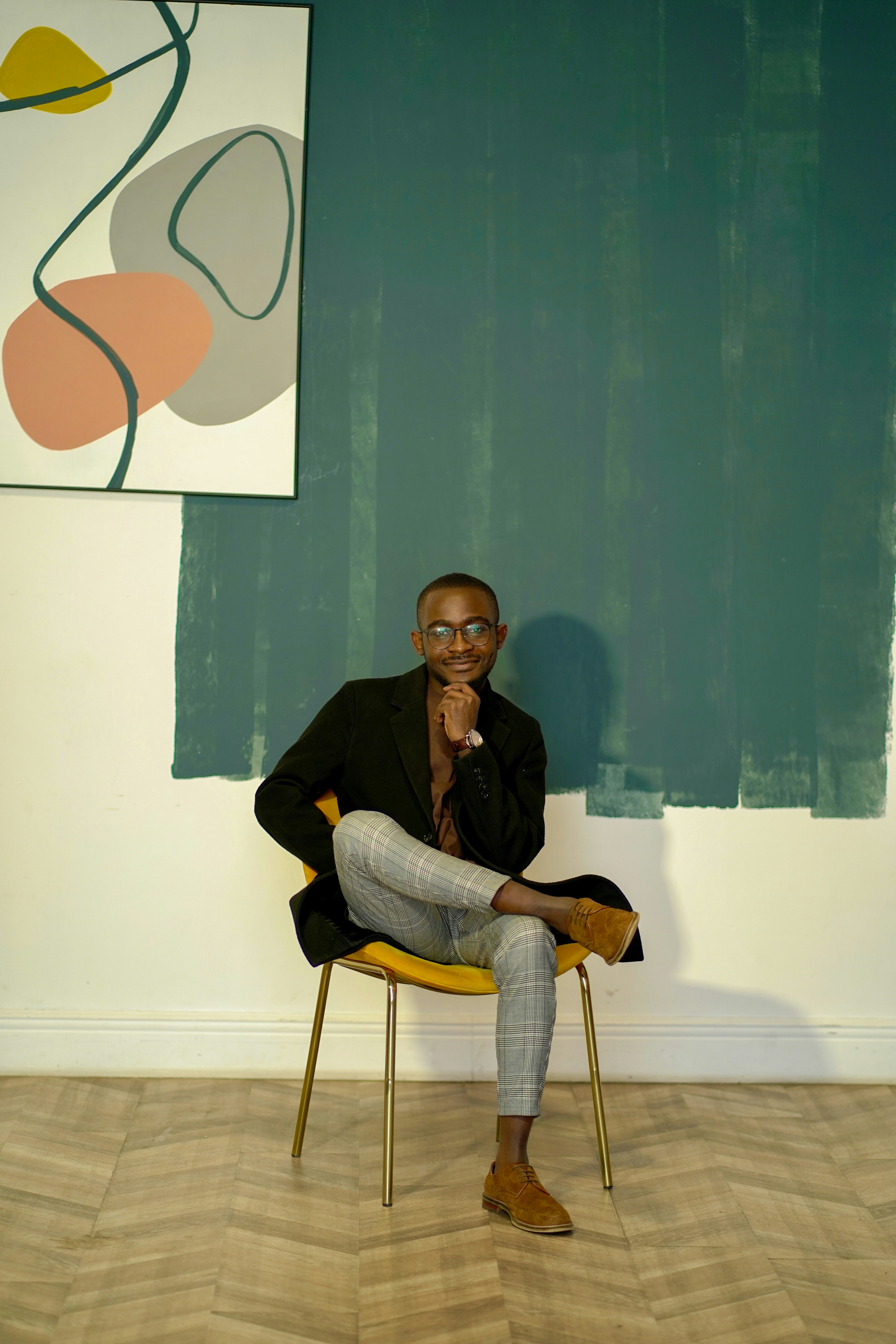 man in black jacket and gray denim jeans sitting on chair