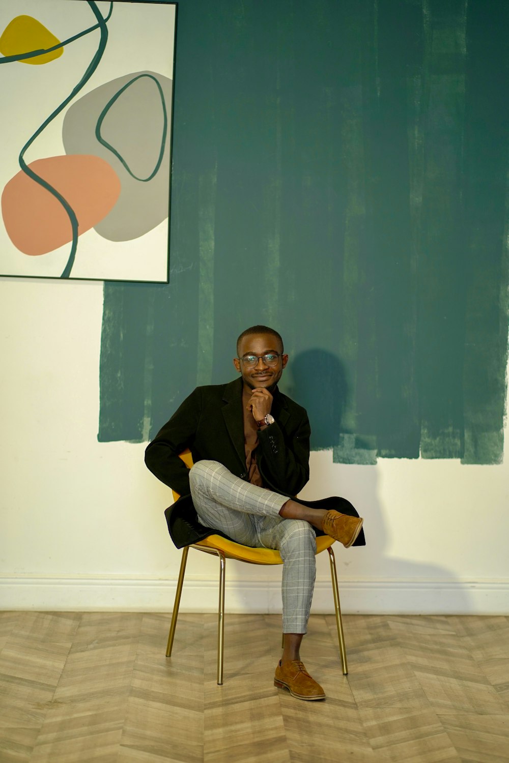 man in black jacket and gray denim jeans sitting on chair