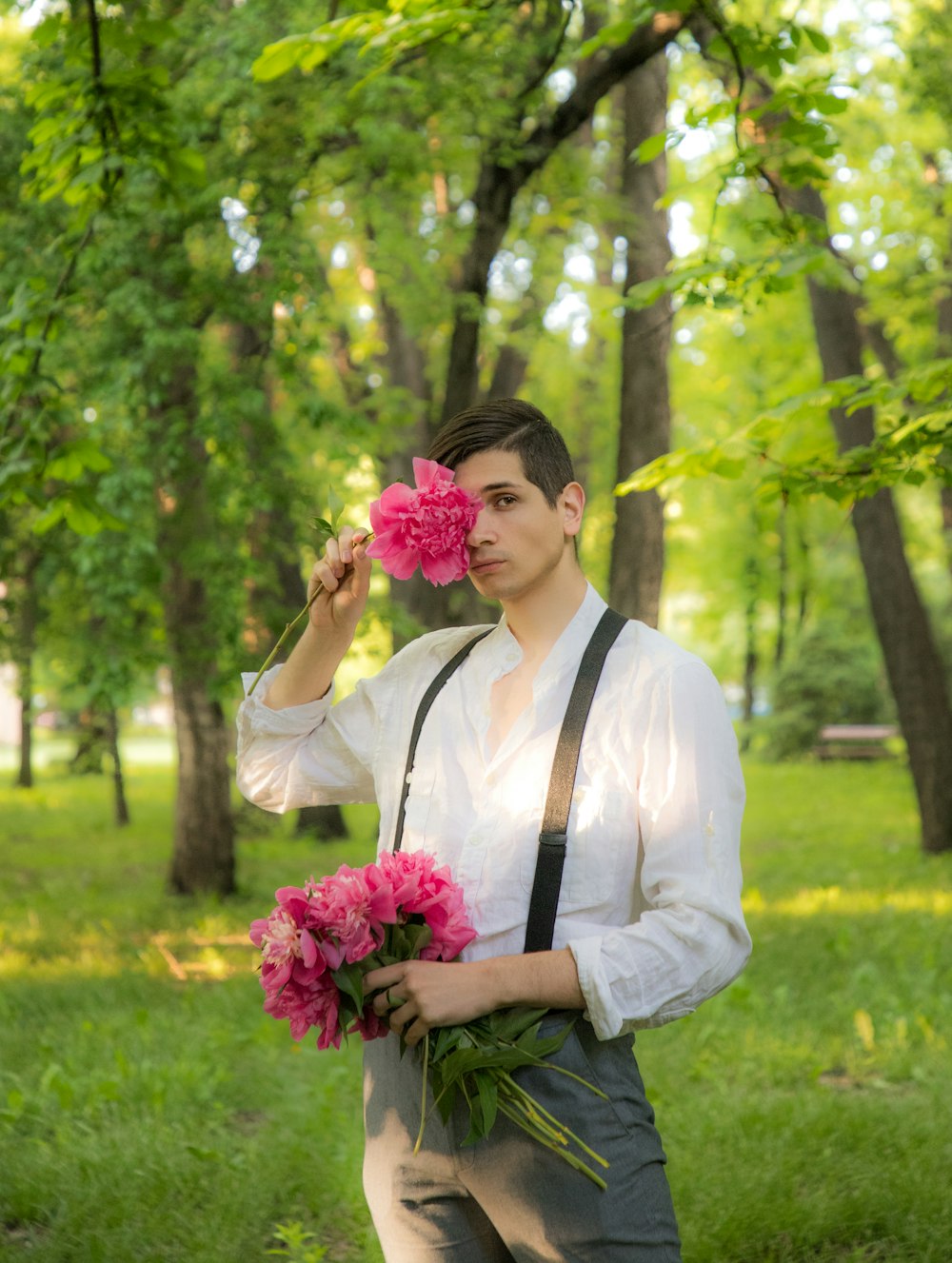 man in white dress shirt holding pink flower bouquet