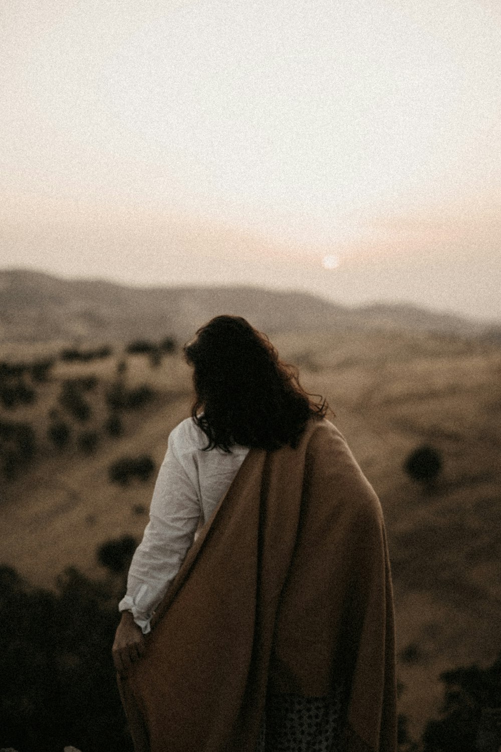 woman in white jacket standing on brown field during daytime