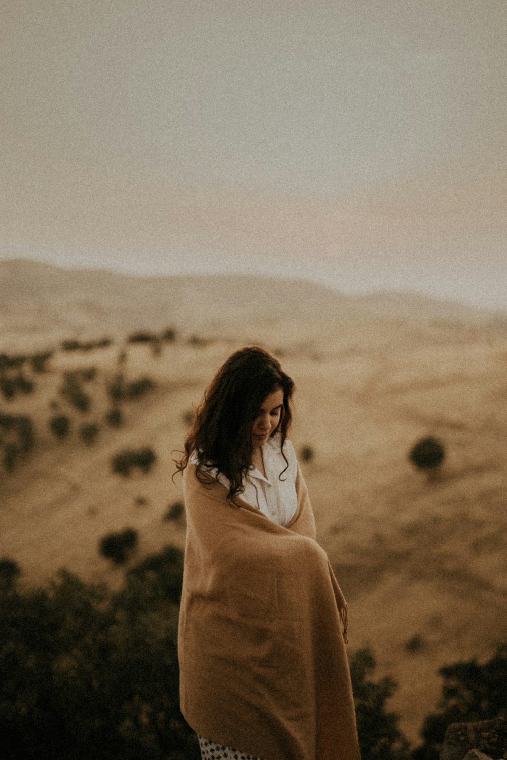 woman in white long sleeve shirt standing on brown field during daytime