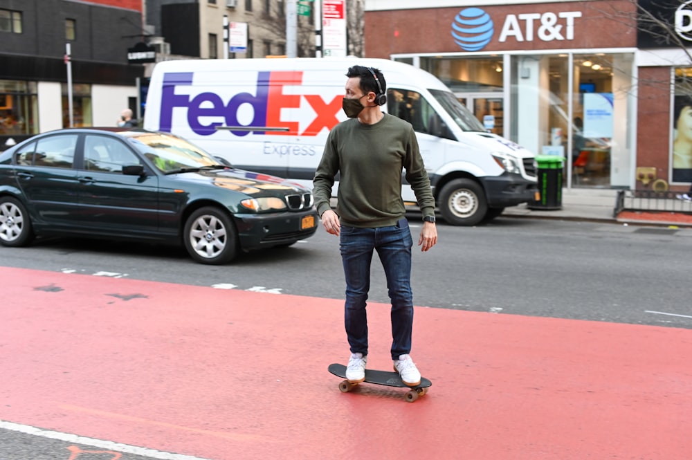 man in gray long sleeve shirt and blue denim jeans standing on red concrete road during