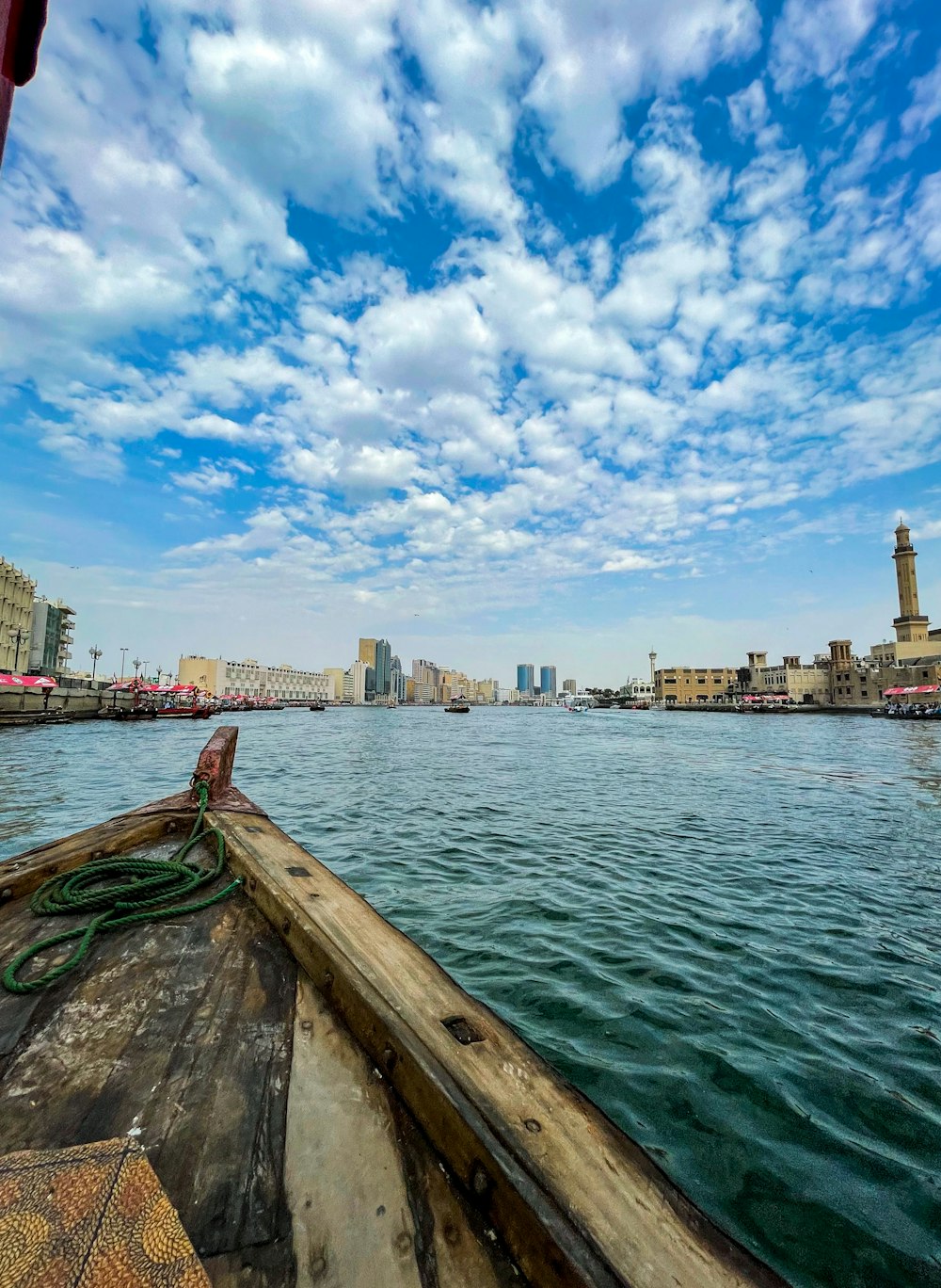 body of water near city buildings under blue and white sunny cloudy sky during daytime