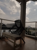 A colorful camping chair on a balcony overlooking a city skyline at dusk.