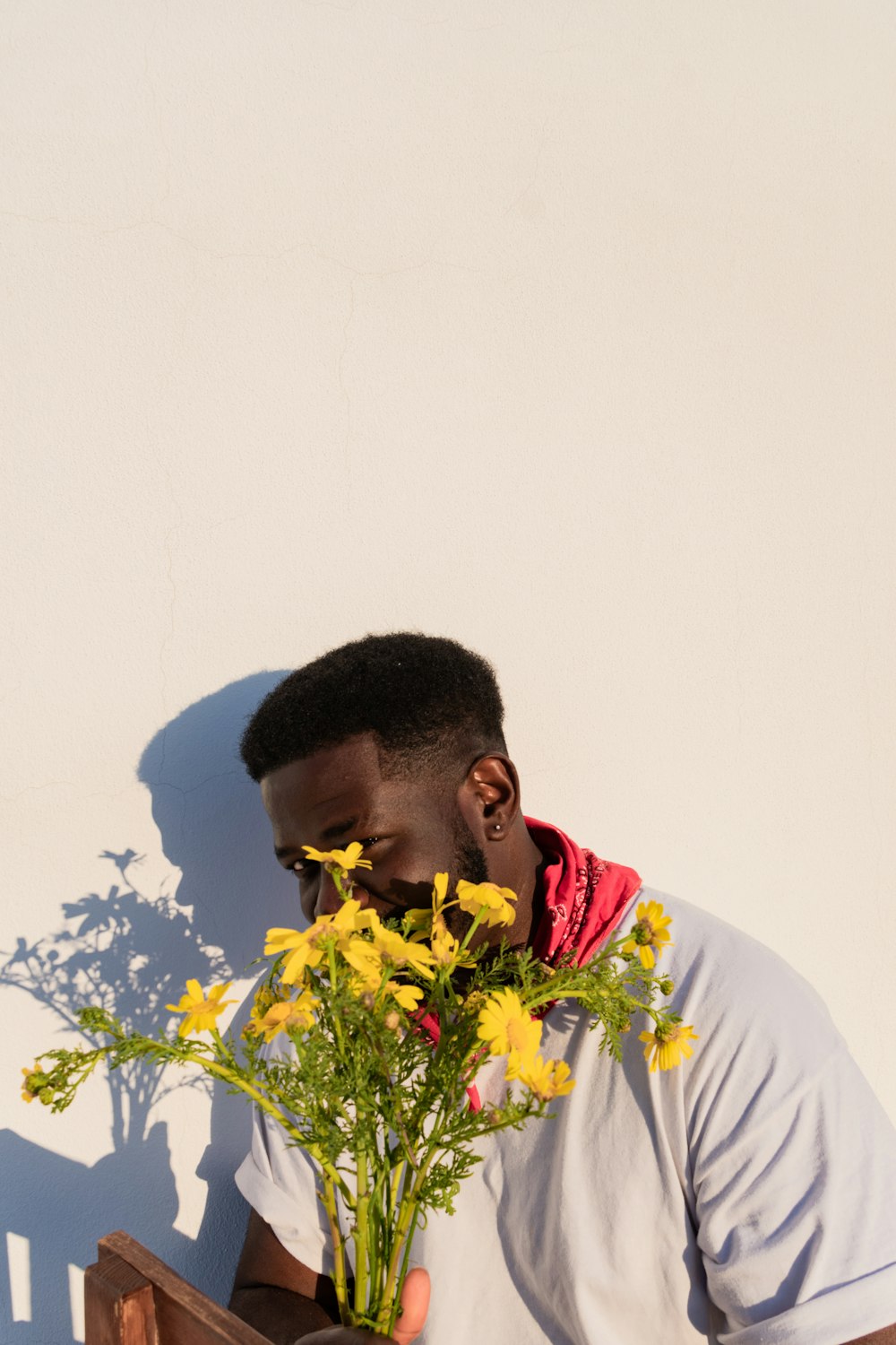 man in white shirt holding yellow flower