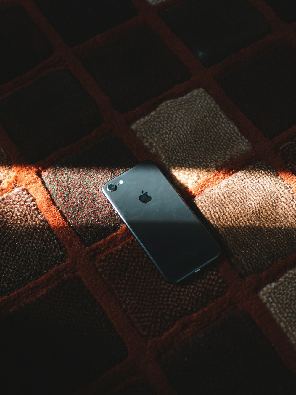 Schwarzes iPhone 4 auf braunem Textil