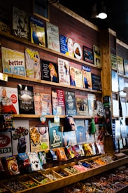 The image depicts a colorful store display featuring an array of vintage-style metal signs and candy packets. The signs display various retro illustrations, humorous quotes, and nostalgic icons. Below the signs, the shelves hold an assortment of bagged candies and snacks, organized in wooden compartments.