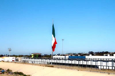 Security personnel monitoring surveillance cameras in a control room with Mexican flag visible.