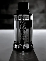 An asymmetrical grid layout featuring a tall, slender bottle with gold embossing against a matte black background.