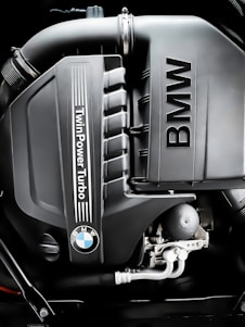 A skilled mechanic carefully inspecting the engine of a BMW in a clean, modern workshop.