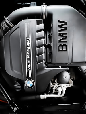 A close-up image of a BMW engine featuring the TwinPower Turbo logo prominently displayed. The engine components are clean and well-defined, showcasing modern automotive engineering.
