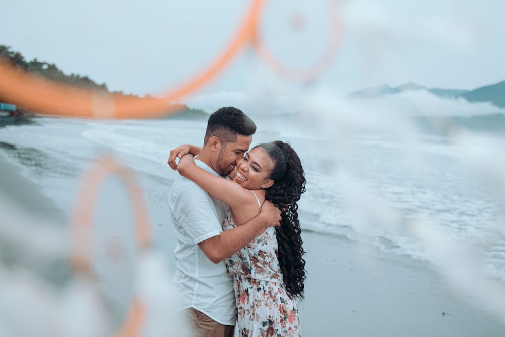 man and woman kissing each other near body of water during daytime