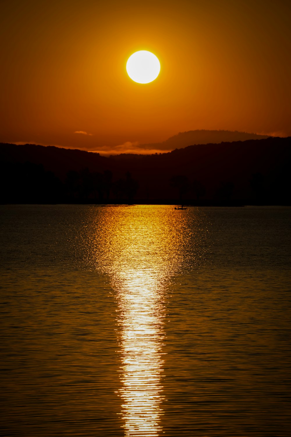 夕暮れ時の水域付近の山のシルエット