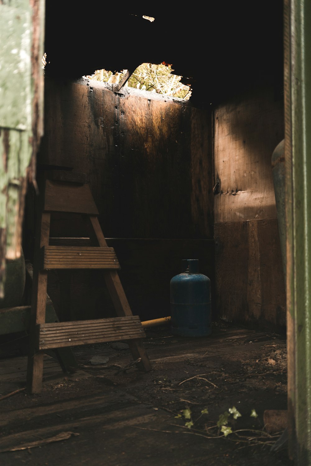 blue propane tank beside brown wooden ladder