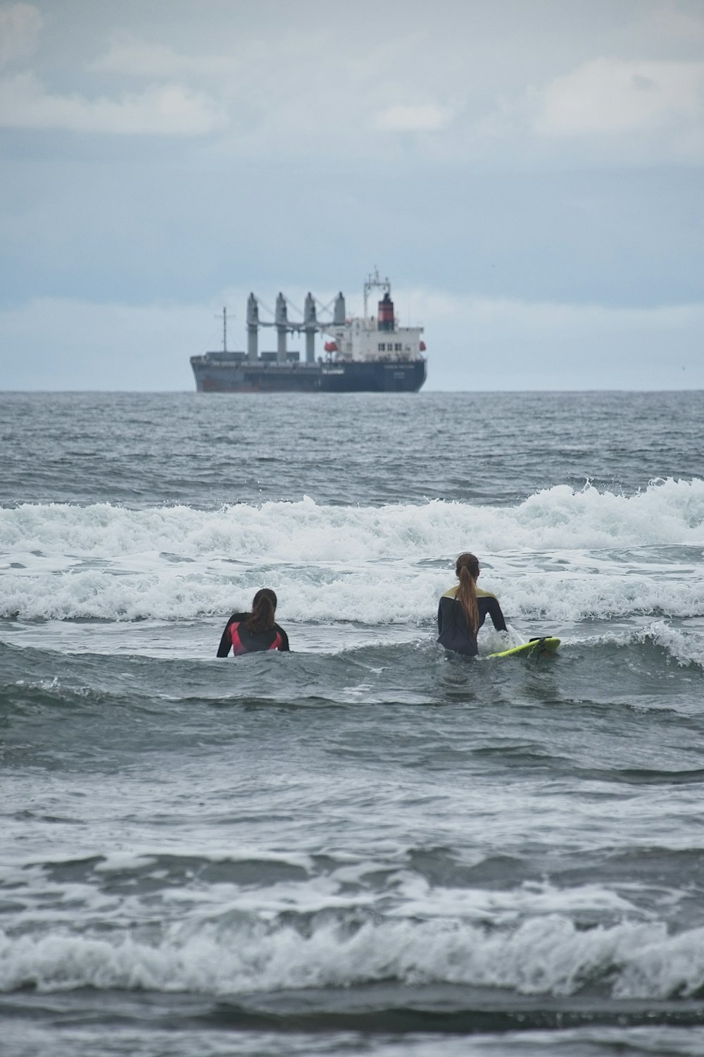 2 people surfing on sea waves during daytime