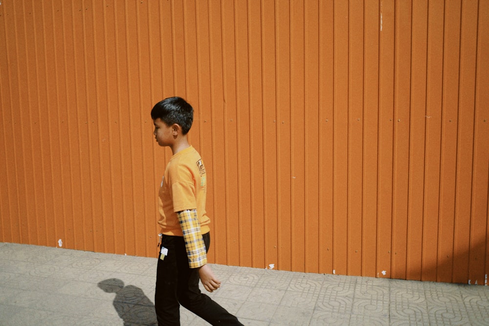 man in yellow crew neck t-shirt and black pants standing on gray concrete floor