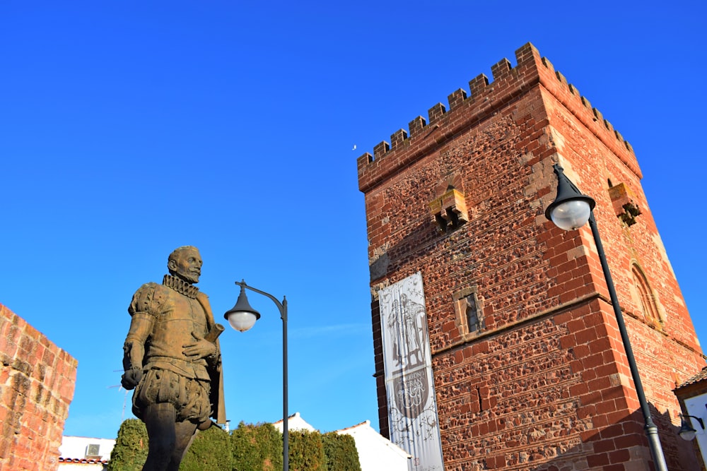 man in black coat statue near brown brick building during daytime