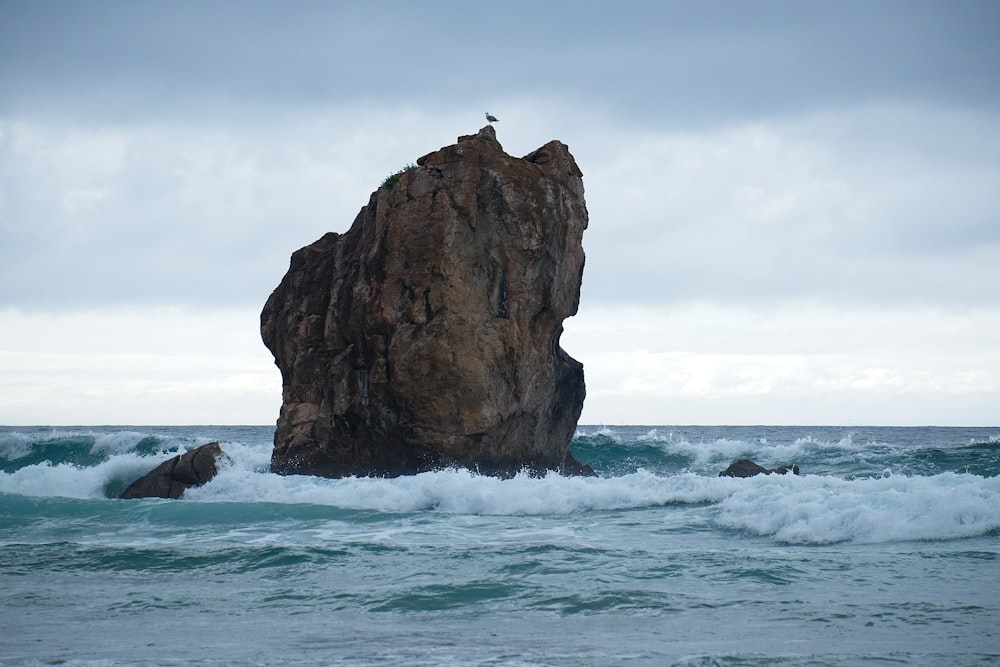 brown rock formation on sea under white clouds during daytime
