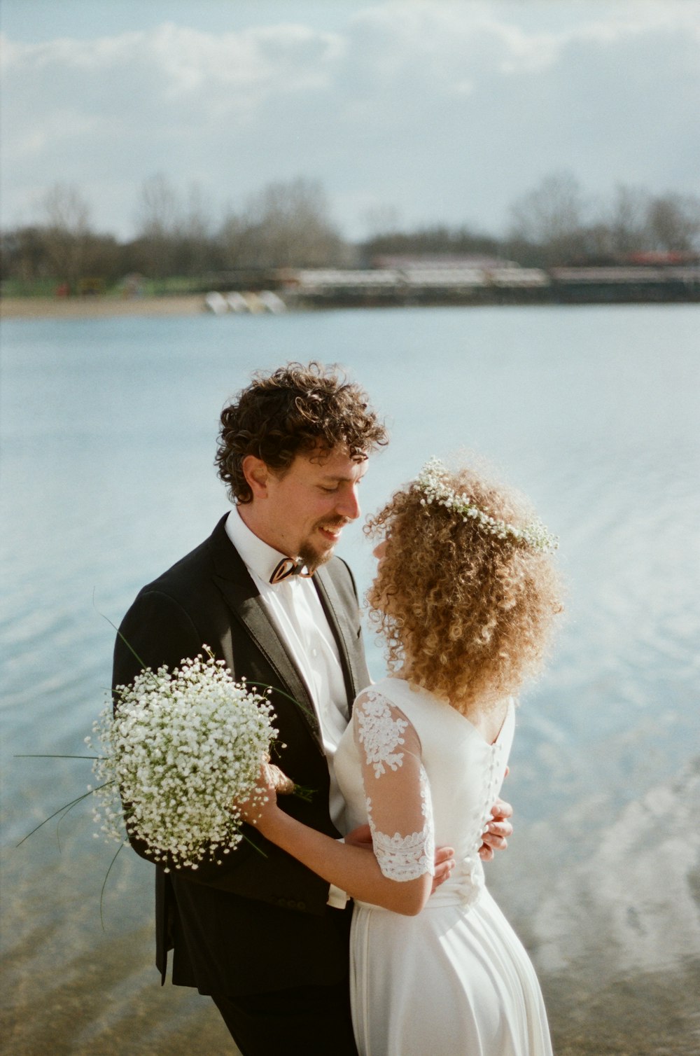 man in black suit kissing woman in white wedding dress