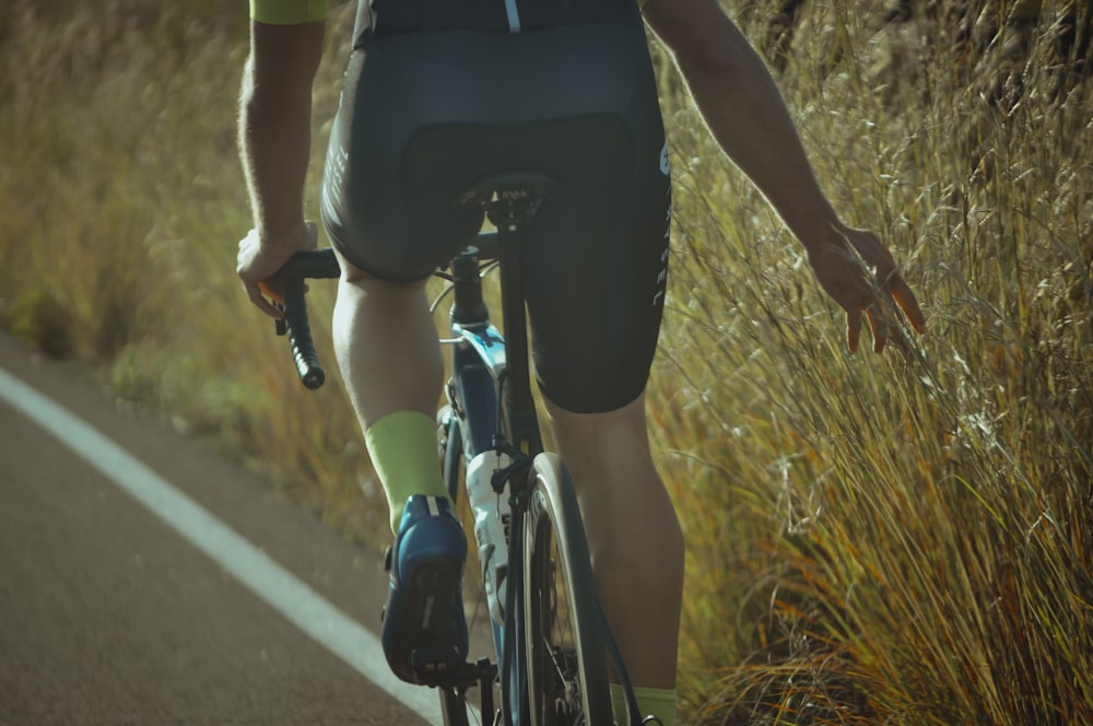 man in black shorts riding bicycle on road during daytime
