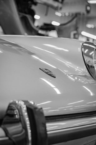 Close-up shot of a rare vintage sports card resting on a sleek car hood.