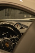 The interior of a luxury car is shown, focusing on the dashboard and central gauge cluster. The steering wheel features a detailed emblem, and the design is sleek and modern with high-quality materials.