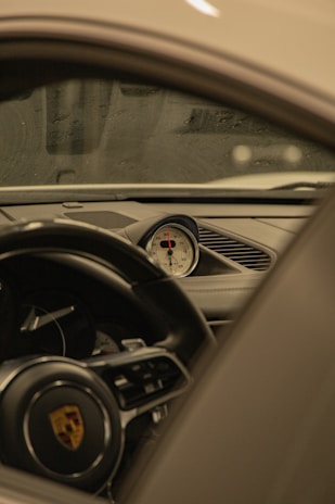 The interior of a luxury car is shown, focusing on the dashboard and central gauge cluster. The steering wheel features a detailed emblem, and the design is sleek and modern with high-quality materials.