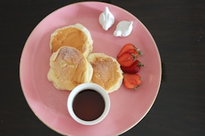 Children in colorful pajamas enjoying pancakes at a decorated table with heart-shaped balloons.