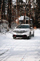 A spacious white SUV driving through a forest trail.