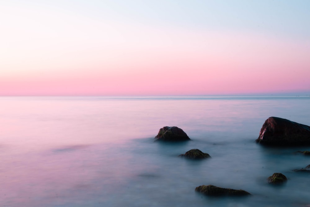 black rock formation on body of water during daytime