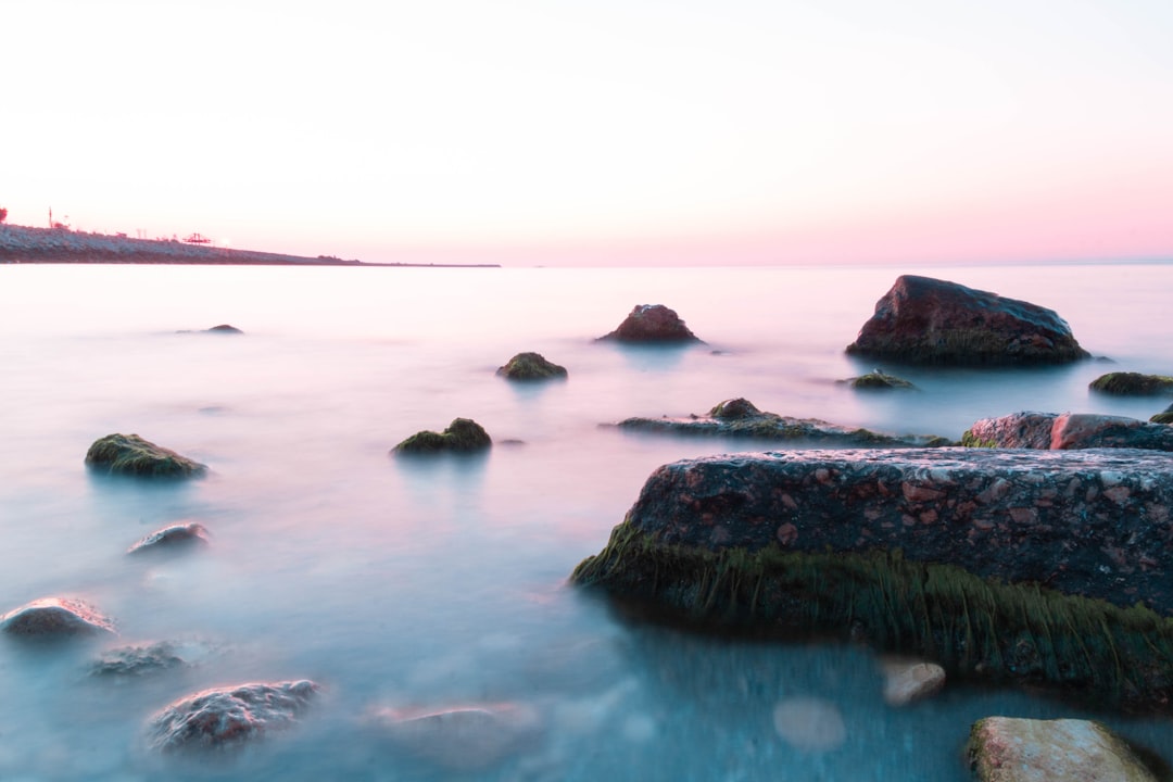 black rock formation on body of water during daytime