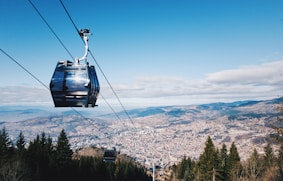 black cable car over green trees and mountains during daytime