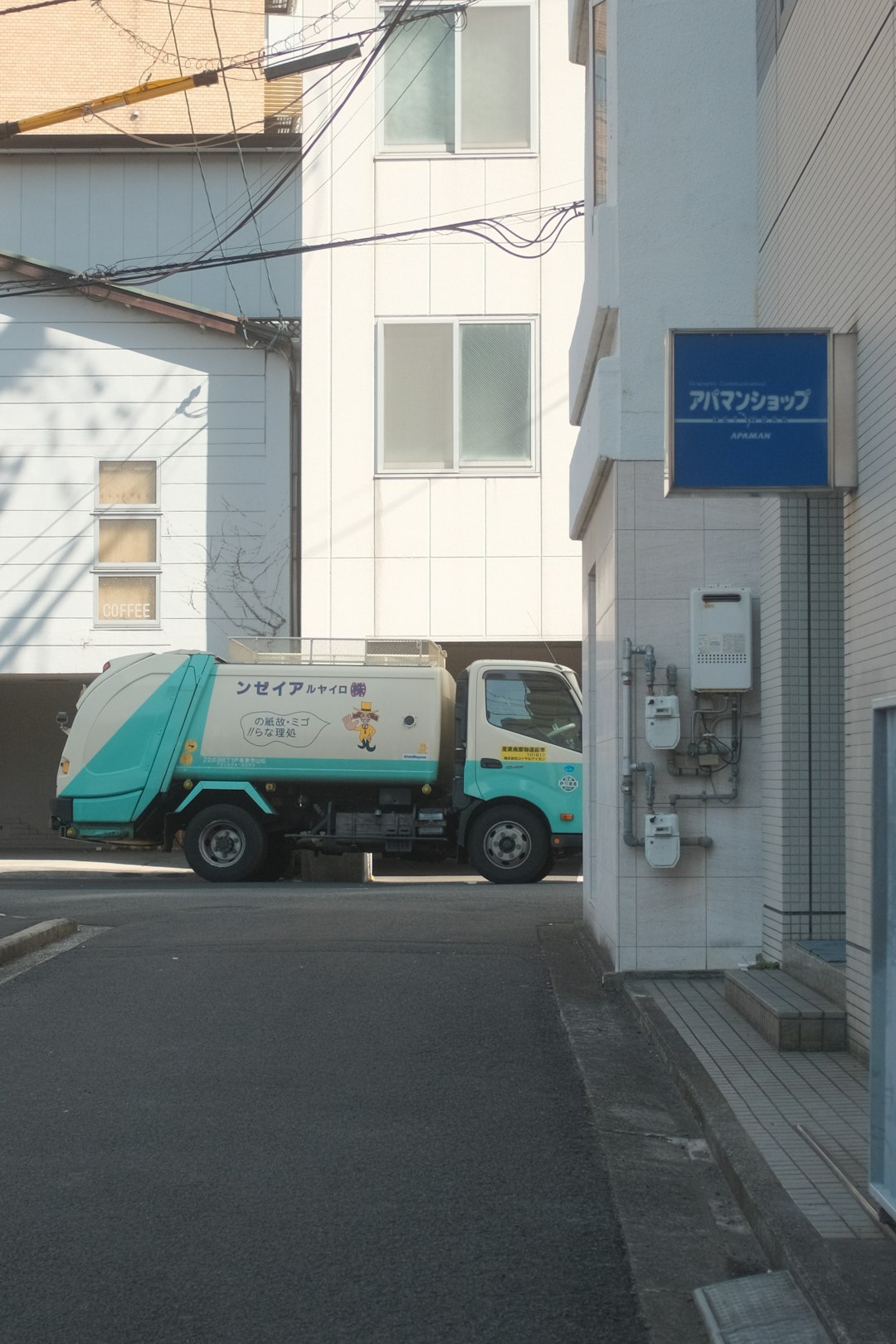 green and white truck parked beside white building during daytime