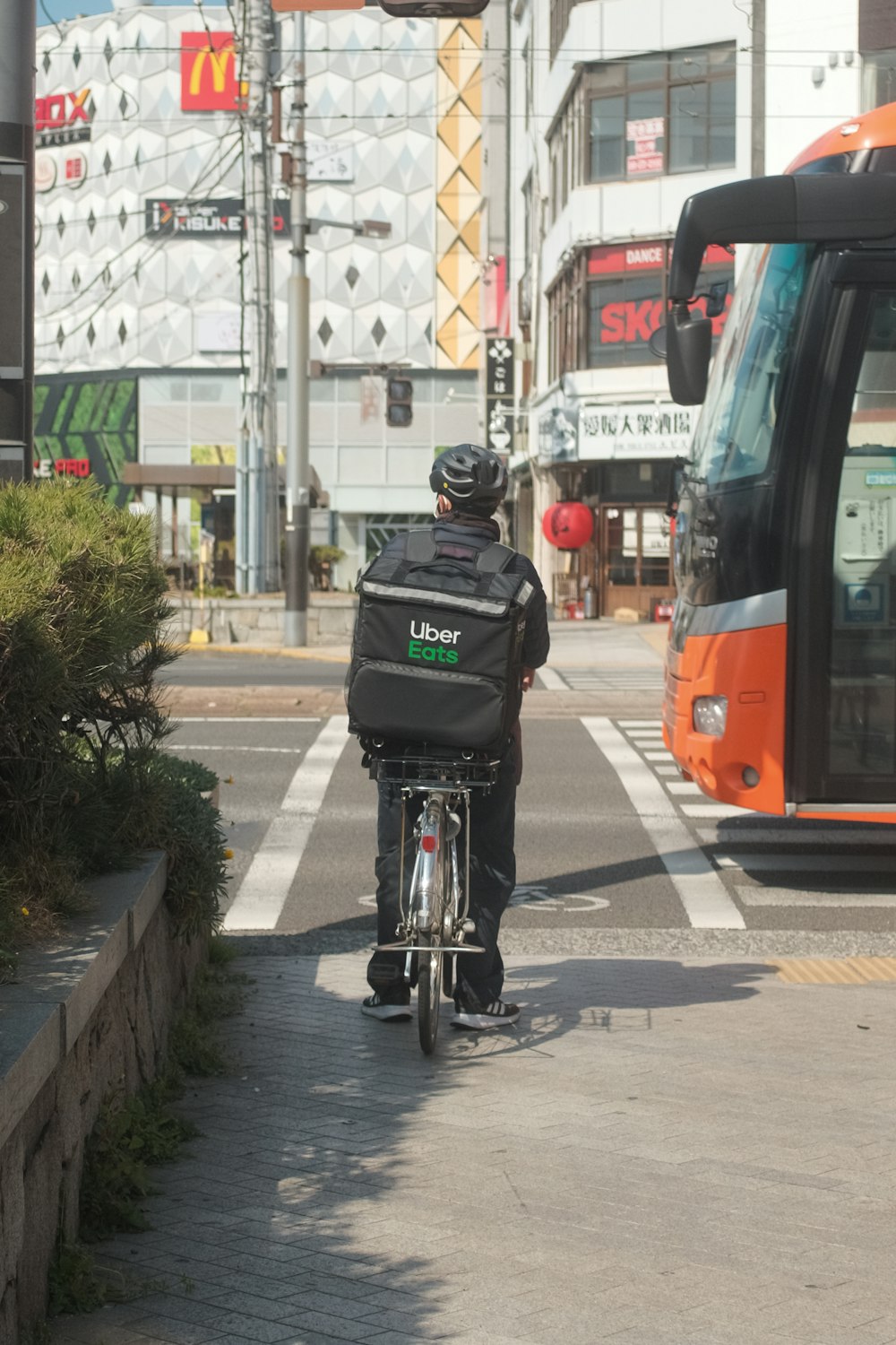 昼間、道路を自転車で走る黒いジャケットの男