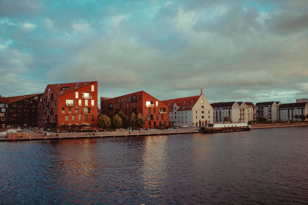 brown and white concrete building beside body of water under cloudy sky during daytime