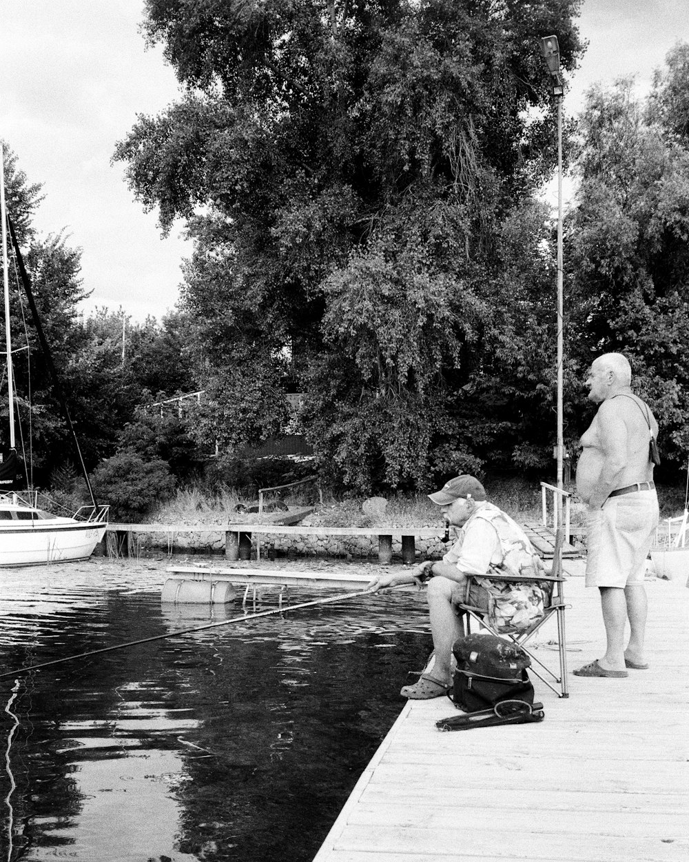 man in white shirt sitting on bench near river