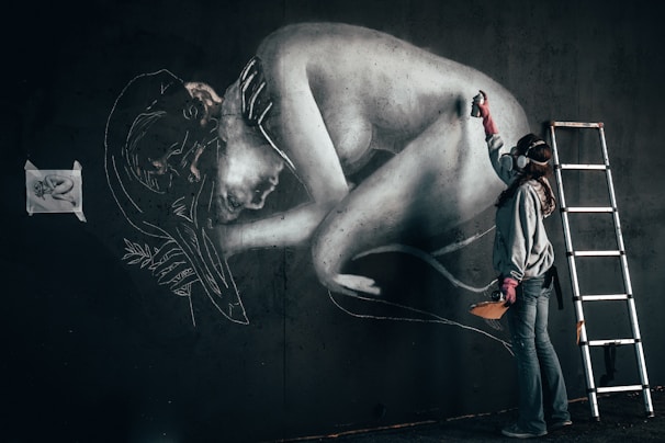 An artist at work, painting a mural on a city wall.