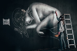 A street artist painting a large mural on a wall.