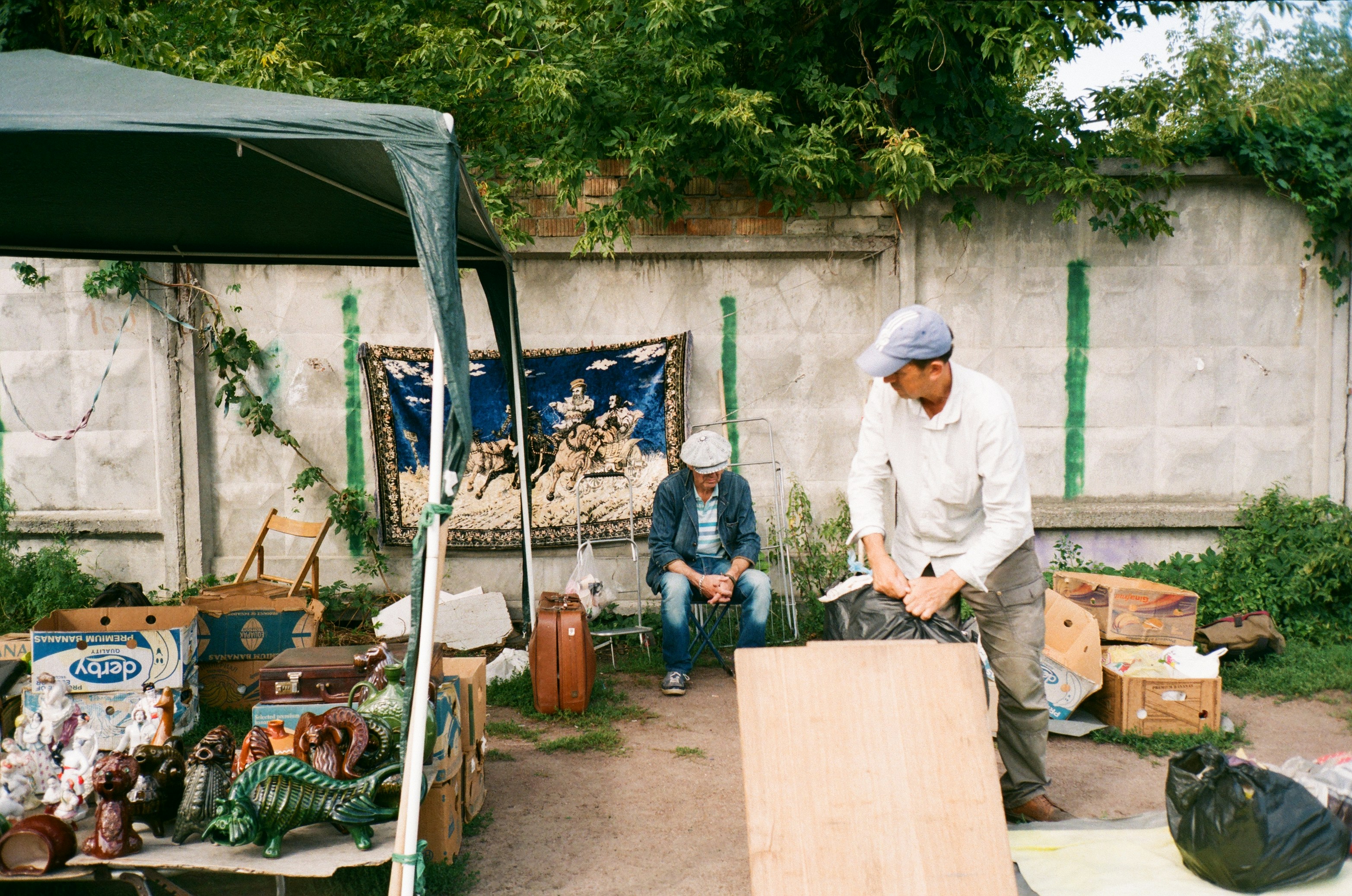 Uomo in camicia bianca a maniche lunghe e cappello bianco che tiene pala nera e arancione
