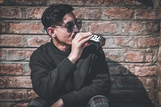 man in black sweater drinking from black and white ceramic mug