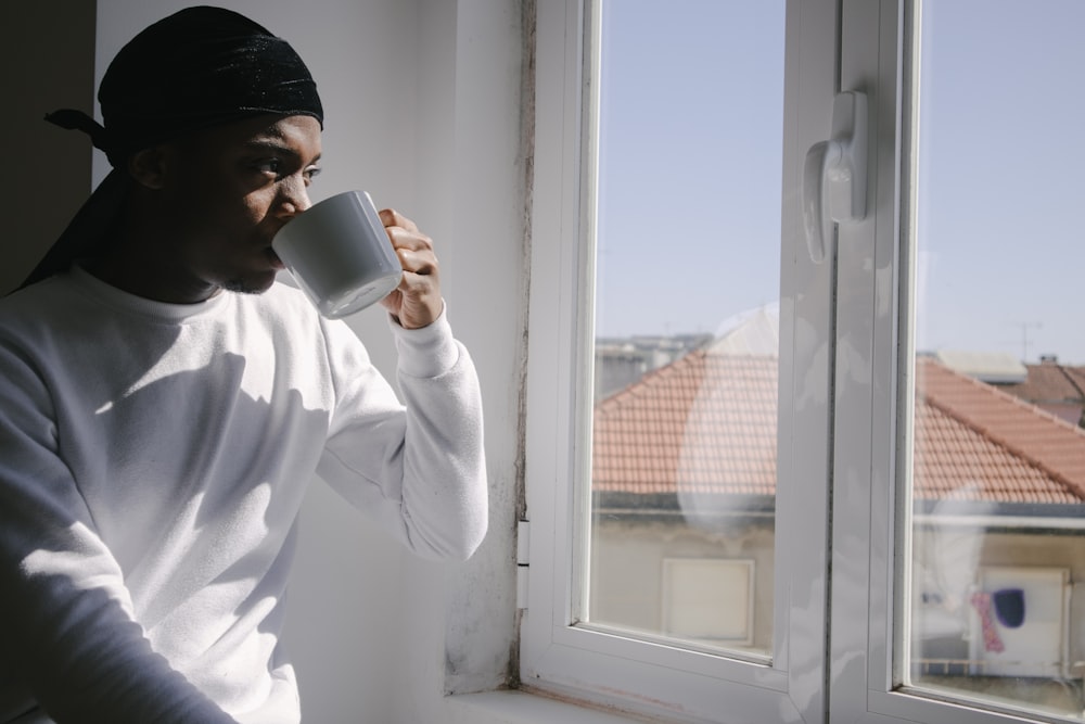 homem na camisa social branca que bebe da caneca de cerâmica branca