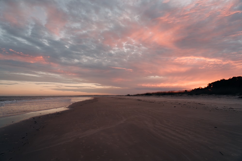 brown sand beach during sunset