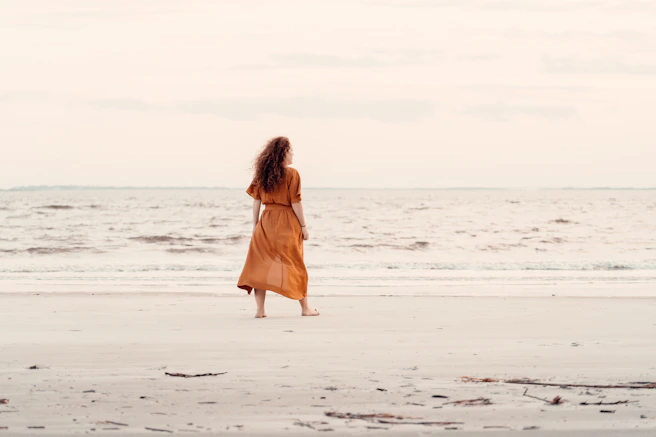 a woman standing on a beach next to the ocean